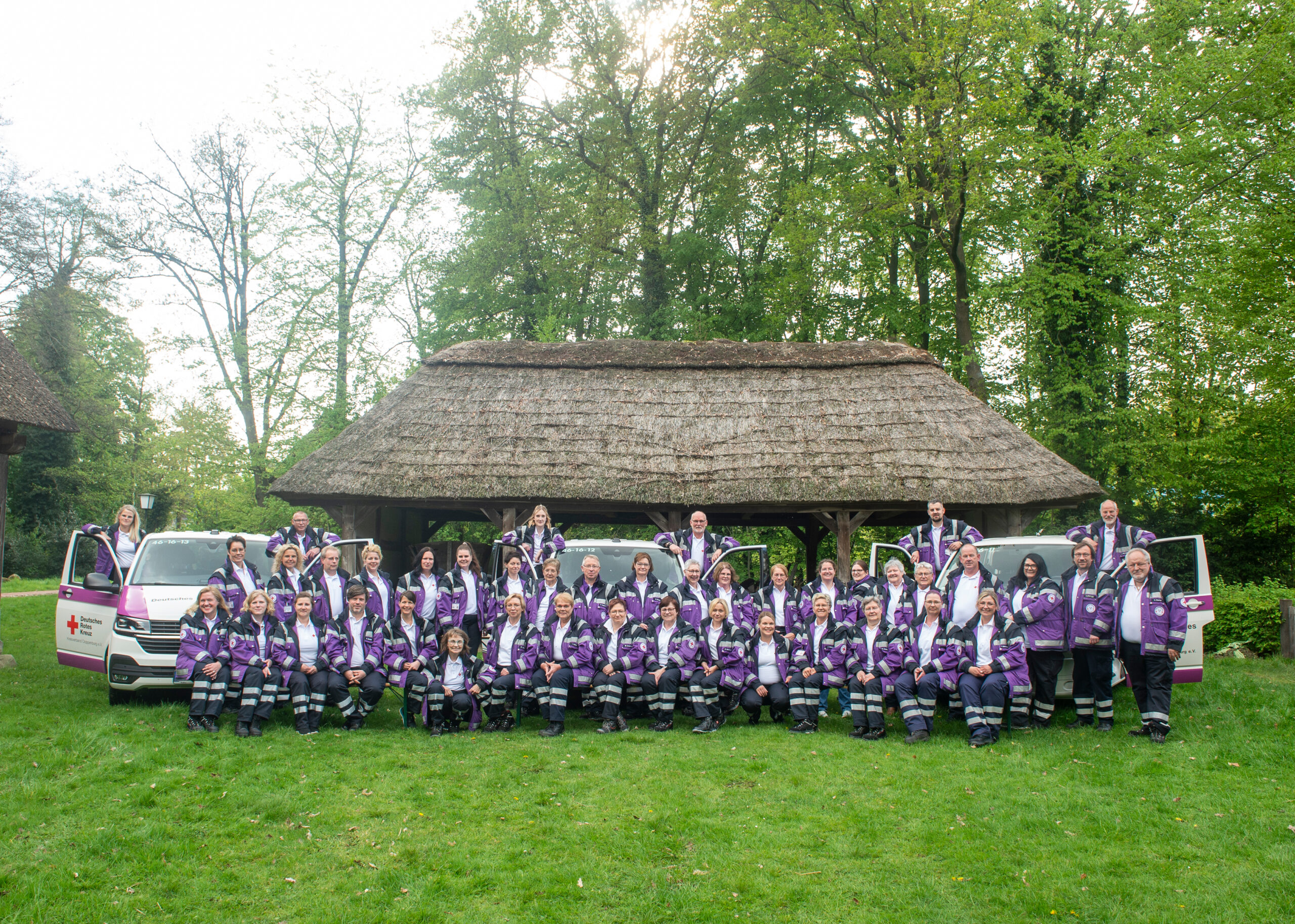 Gruppenfoto des PSNV-Teams vor einem reetgedeckten Haus mit Einsatzfahrzeugen